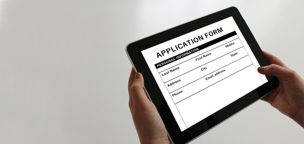 Ein Mensch hält ein Pad mit einer Datei "Application form".