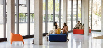 Zwei Studentinnen sitzen auf Sofas in einem Gebäude des Campus Lippstadt und unterhalten sich.